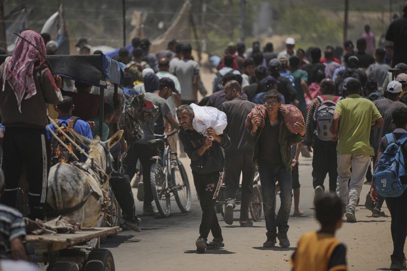 Palestinos llevan bolsas con alimentos y paquetes de ayuda humanitaria entregados por la Fundación Humanitaria de Gaza, organización respaldada por Estados Unidos, en Rafah