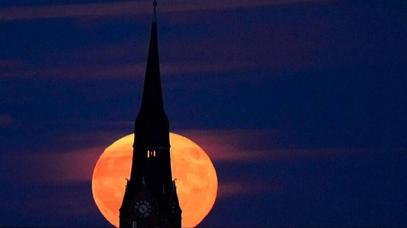 La pleine lune des fraises se lève derrière une église à Berlin, en Allemagne, le mardi 14 juin 2022.