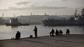 Local fishermen try to catch fish in front of Russia Navy ships in Sevastopol, Crimea, Oct. 27, 2014.