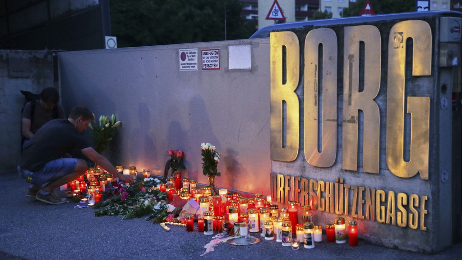 A man places a candle at the entrance of a school after a deadly shooting took place there, in Graz, Austria, Tuesday, June 10, 2025