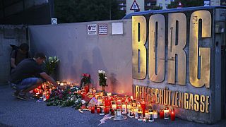 A man places a candle at the entrance of a school after a deadly shooting took place there, in Graz, Austria, Tuesday, June 10, 2025