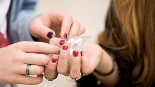 A teenager offers pills to a friend.