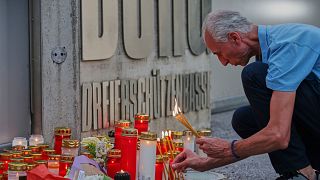 A man lights candles at the entrance of a school, after a deadly shooting there, in Graz, Austria, Tuesday, June 10, 2025.