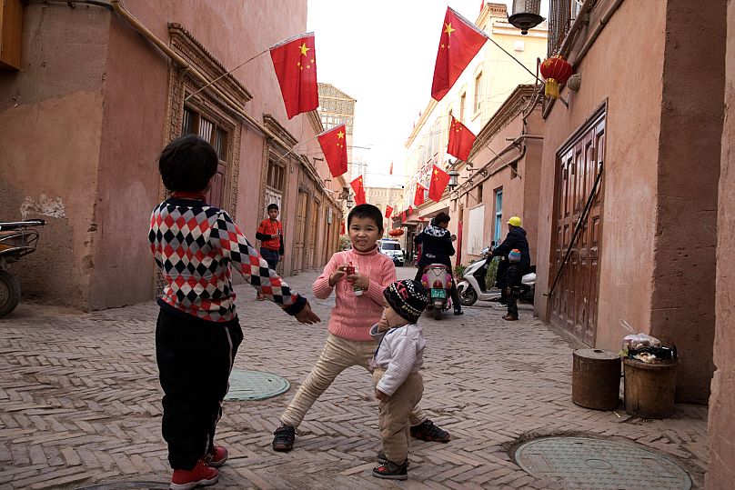 Des enfants jouent dans la vieille ville de Kashgar, où des drapeaux chinois sont accrochés en évidence, dans la région du Xinjiang, le 4 novembre 2017