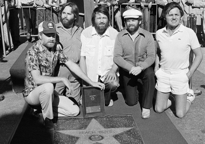 Membros dos The Beach Boys, com Brian Wilson ao centro, posam com a sua estrela no Passeio da Fama de Hollywood durante uma cerimónia em Los Angeles, a 30 de dezembro de 1980.