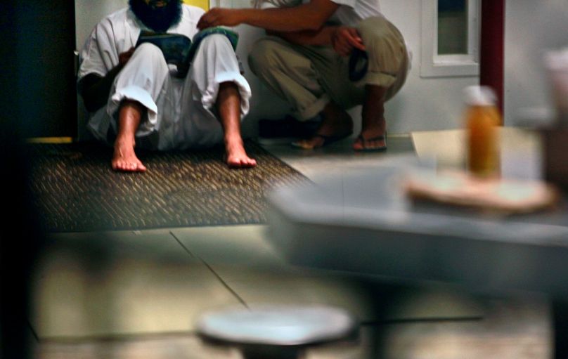  في هذه الصورة الملتقطة يوم الثلاثاء 12 مايو/أيار 2009، يجلس معتقلو غوانتانامو معًا وهم يقرؤون مجلة في منطقة مشتركة. 