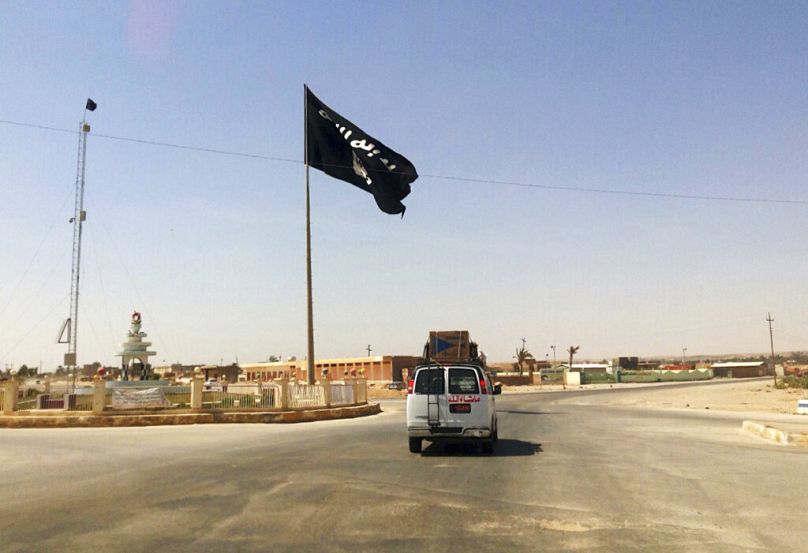 سيارة تمرّ بجانب علم لتنظيم الدولة الإسلامية في وسط مدينة راوة، العراق، في  22 تموز/ يوليو 2014.