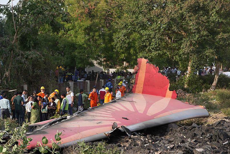 Persone intorno ai resti dell'aereo precipitato nella città nord-occidentale di Ahmedabad, in India (12 giugno 2025)