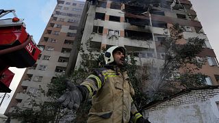 یک آتش‌نشان در صحنه انفجار در یک مجتمع مسکونی در شمال تهران، ایران، جمعه، ۱۳ ژوئن ۲۰۲۵ همکارانش را صدا می‌زند