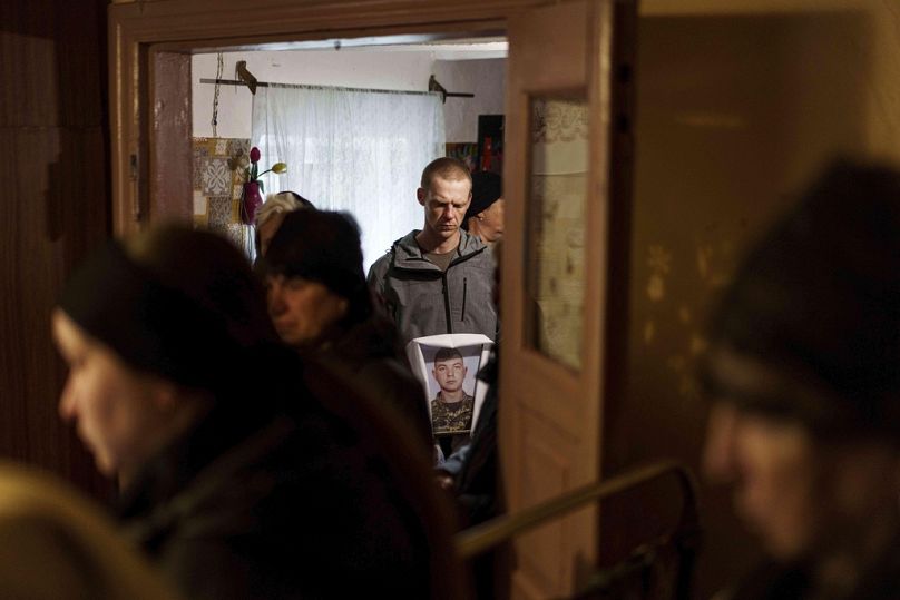 Bir adam, Vinnytsia bölgesindeki Yosypivka köyündeki cenaze töreni sırasında Ukraynalı asker Dmytro Shapovalov'un fotoğrafını tutuyor, 13 Haziran 2025.