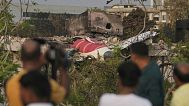 Onlookers watch wreckage from Thursday's Air India plane crash lying atop a building in Ahmedabad, India, Saturday, June 14, 2025.