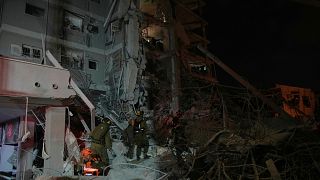 Israeli security forces inspect destroyed buildings that were hit by a missile fired from Iran, near Tel Aviv, Israel, early Sunday, June 15, 2025.