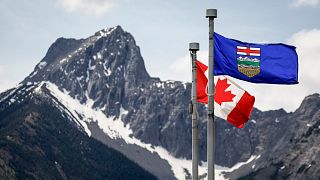 Una bandera de Canadá, a la izquierda, y una bandera de Alberta ondean en la brisa con la montaña Wedge al fondo en el lugar de la reunión de líderes del G7 en Kananaskis, Alberta, 2 de junio de 2025.