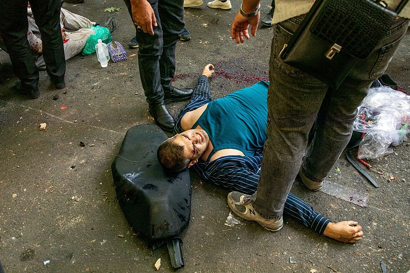 Раненый мужчина на земле после взрыва в центре Тегерана на третий день израильских авиаударов по Ирану, 15 июня 2025 г.