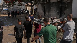 FILE - Palestinians carry the body of a person who died last night while trying to get access to humanitarian aid, near the al-Shifa Hospital, in Gaza City, Wednesday, June 11