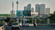 وسایل نقلیه در بزرگراه با برج‌های مسکونی و برج مخابراتی میلاد قابل مشاهده در پس زمینه در شمال تهران، ایران، جمعه ۱۳ خرداد ۲۰۲۵ رانندگی می‌کنند. 