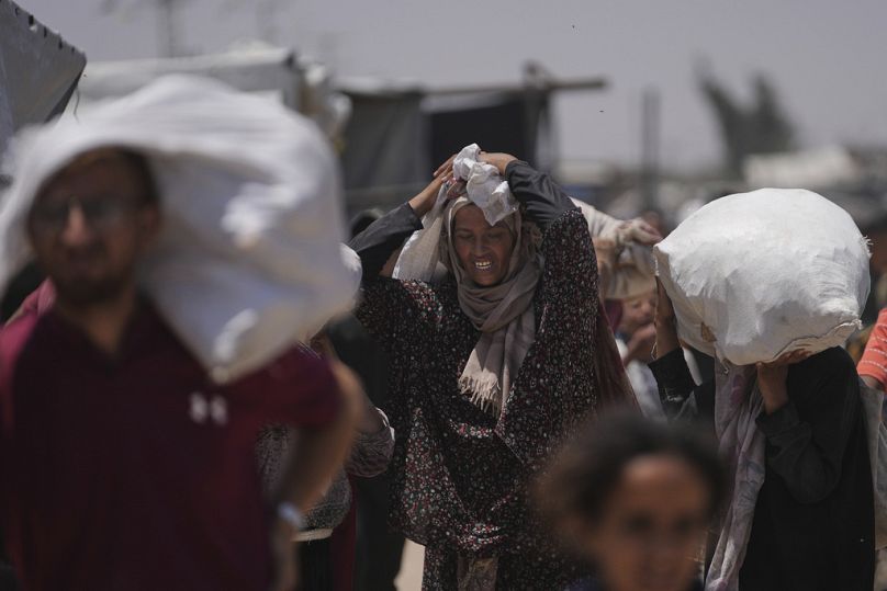 فلسطينيون يحملون أكياسًا تحتوي على مساعدات غذائية وإنسانية وزّعتها "مؤسسة غزة الإنسانية" المدعومة من الولايات المتحدة، في رفح جنوب قطاع غزة، يوم الاثنين 16 حزيران/يونيو 2025.