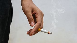 A woman holds a cigarette.
