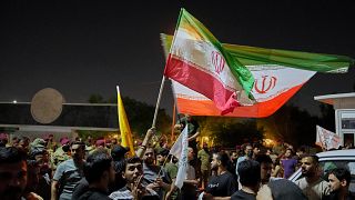 Protesters carry Iranian flags during a protest against Israeli attacks on Iran, near the fortified Green Zone where the US embassy is located in Baghdad, 17 June 2025
