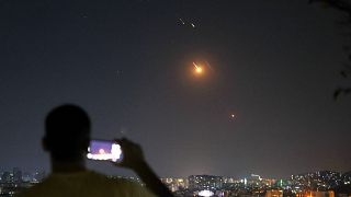 A man takes a cellphone photo as missiles fired from Iran toward Israel fly over Syrian territory in Damascus, 18 June 2025