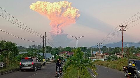 People watch as Mount Lewotobi Laki-Laki spews volcanic materials into the air during an eruption, in Maumere, Indonesia.