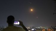 A man takes a cellphone photo as missiles fired from Iran toward Israel fly over Syrian territory in Damascus, Syria, early Wednesday, June 18, 2025.