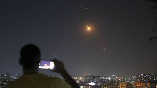 A man takes a cellphone photo as missiles fired from Iran toward Israel fly over Syrian territory in Damascus, Syria, early Wednesday, June 18, 2025.