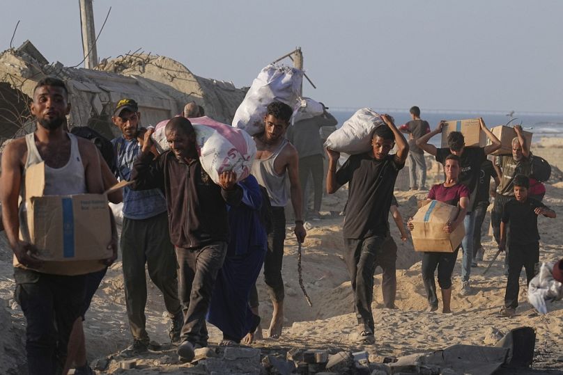 فلسطينيون يحملون أكياسًا غذائية بعد أ حصلوا عليها من قافلة تابعة لبرنامج الأغذية العالمي، شمال قطاع غزة، الإثنين 16 حزيران/ يونيو 2025.