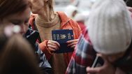 A woman holds Ukrainian passports as she waits to register for a bus which will take refugees to Germany, at the train station in Przemysl, Poland, Thursday, March 3, 2022. 