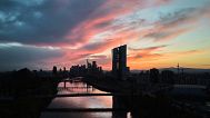 The sun sets behind the European Central Bank building, foreground center, in Frankfurt, Germany. 26 April 2025.