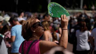 A woman uses a fan to shade her face from the sun in London during the heatwave on 18 July 2022.