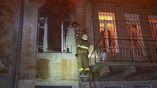 In this photo provided by the Ukrainian Emergency Service, firefighters evacuate a resident from the burning apartment building following Russia's massive air attack in Odesa.
