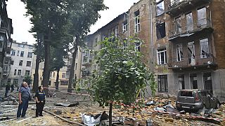 People look at a burnt apartment building following Russia's massive air attack in Odesa, Ukraine, Friday, June 20, 2025;