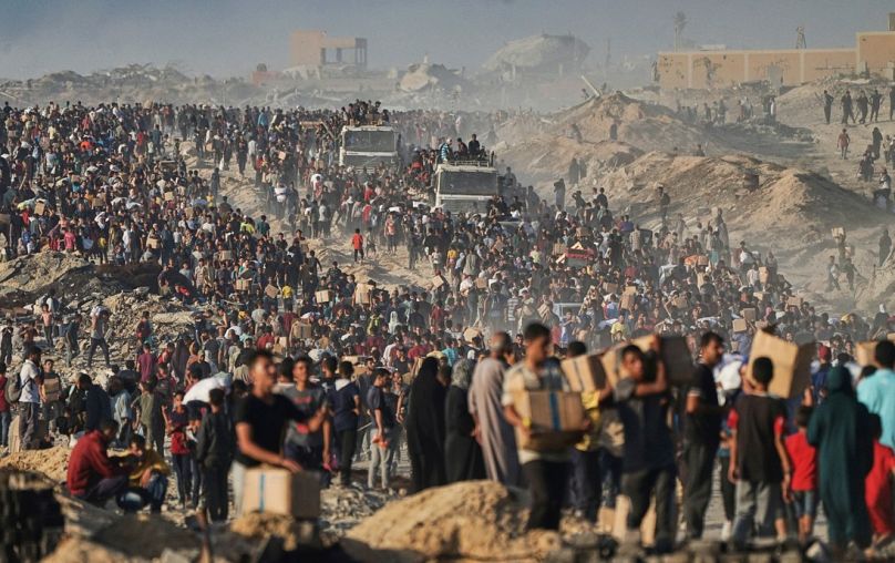 يحمل فلسطينيون أكياسًا وصناديقًا من الطعام والمساعدات الإنسانية التي تم تفريغها من قافلة برنامج الغذاء العالمي، الاثنين 16 يونيو 2025. 