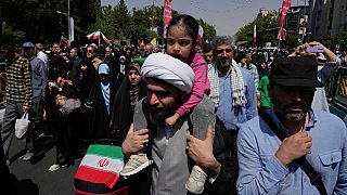 A cleric carries a small child on his shoulder during a demonstration to denounce Israeli attacks on several cities across Iran, after Friday prayers in Tehran, Iran, Friday, 20 June 2025