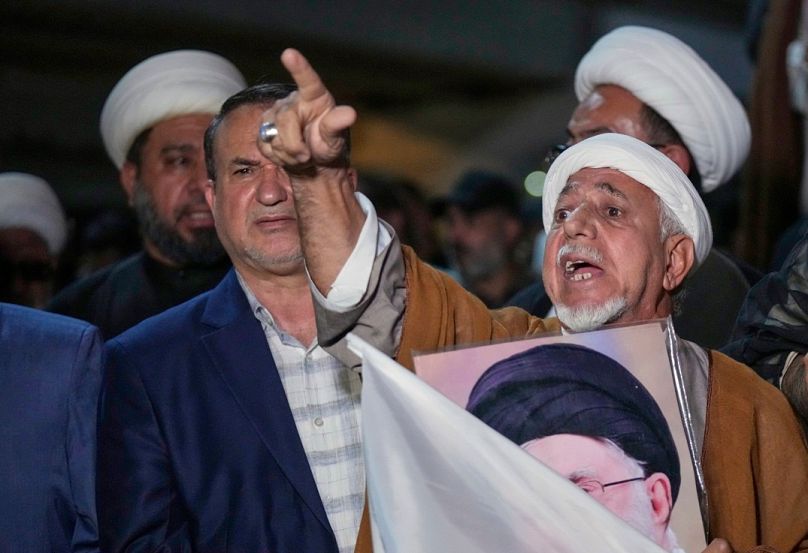 رجل دين شيعي عراقي يحمل صورة المرشد الأعلى الإيراني آية الله علي خامنئي، العراق، الخميس 19 يونيو 2025.  