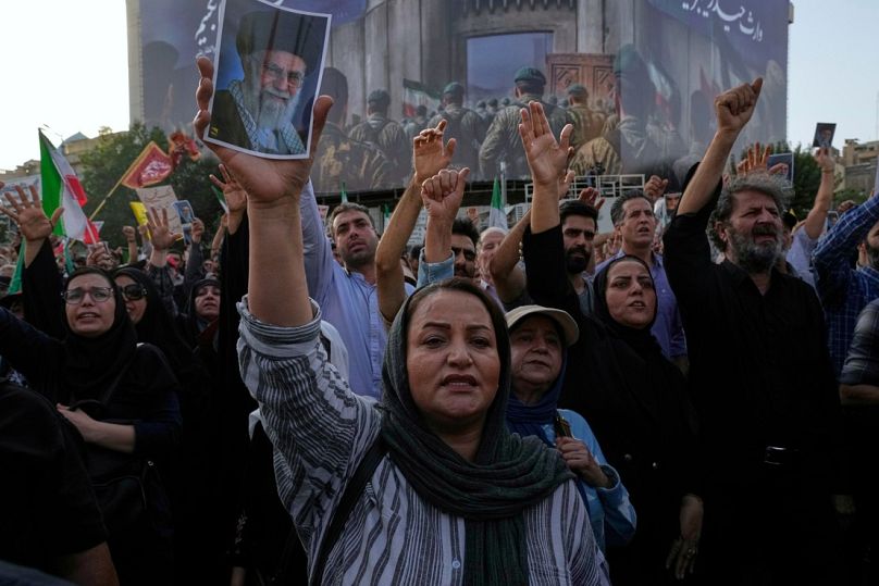 يردد المتظاهرون شعارات بينما يحمل أحدهم ملصقًا للمرشد الأعلى الإيراني آية الله علي خامنئي، إيران، الأحد 22 يونيو 2025.  