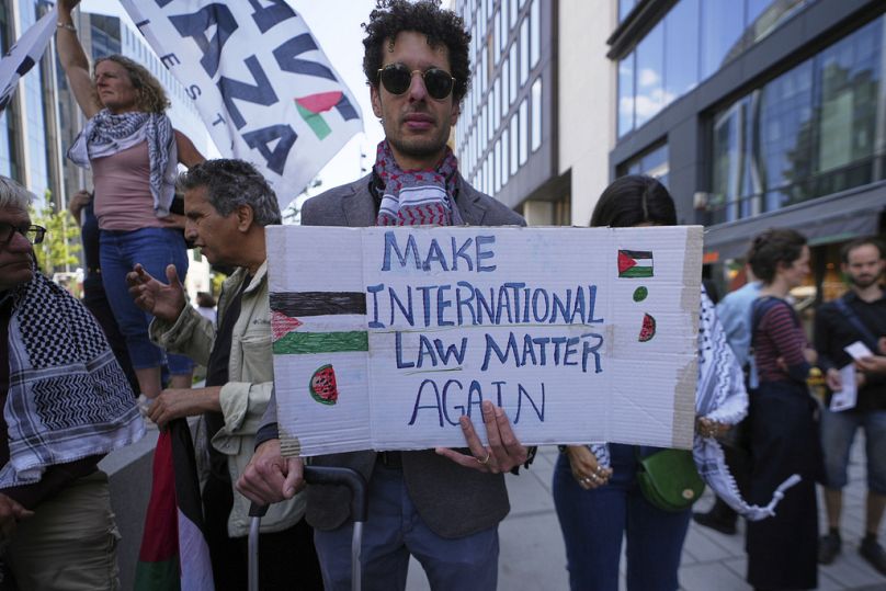 متظاهر يرفع لافتة دعمًا للفلسطينيين خارج اجتماع لوزراء خارجية الاتحاد الأوروبي في بروكسل – 23 حزيران/ يونيو 2025.