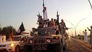 Islamic State militants parade in a commandeered Iraqi security forces armoured vehicle in the northern city of Mosul, 23 June, 2014