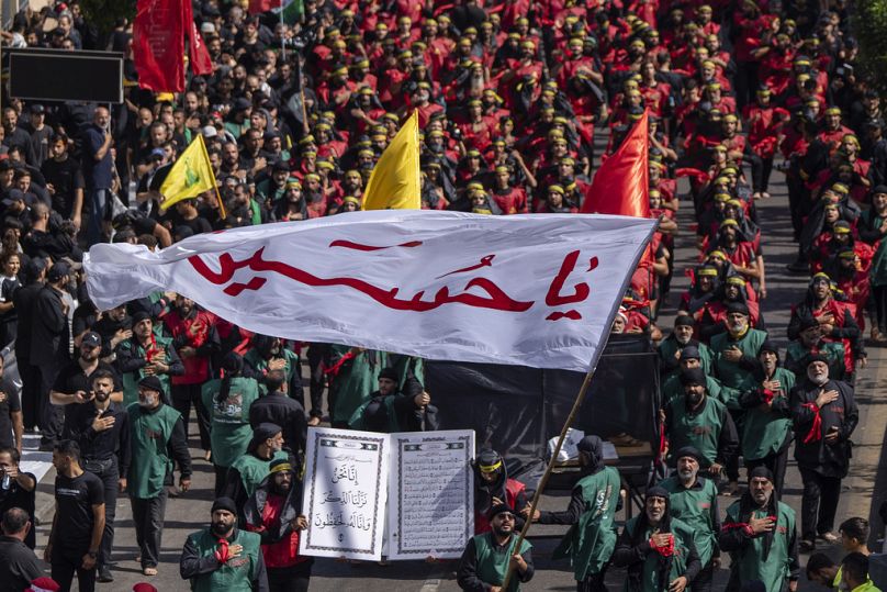 مناصر لحزب الله يلوّح براية كُتب عليها "يا حسين" خلال مسيرة عاشوراء في الضاحية الجنوبية لبيروت، السبت 29 تموز/ يوليو 2023.