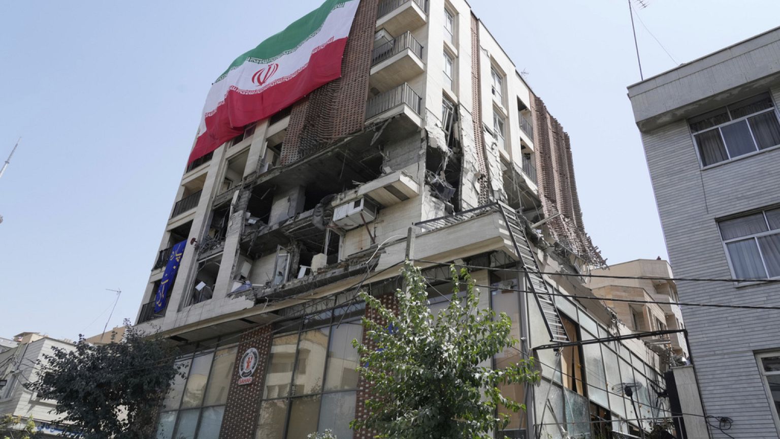 Una bandera iraní cuelga de un edificio alcanzado por un ataque israelí la semana pasada, en Teherán, Irán, miércoles 25 de junio de 2025.