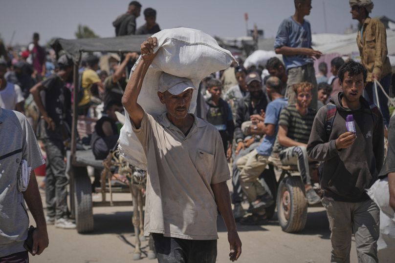 فلسطينيون يحملون مساعدات غذائية وإنسانية، في رفح جنوب قطاع غزة، 26 حزيران/يونيو 2025.