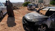 Women comfort each other by a vehicle that was burnt overnight by Israeli settlers in an attack that left three Palestinians killed and burnt several vehicles and damaged home
