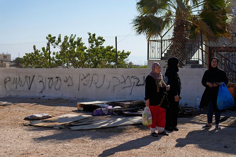 Las mujeres permanecen junto a su casa, que fue parcialmente quemada durante la noche por colonos judíos en la aldea de Kafr Malik, en Cisjordania, el 26 de junio de 2025.