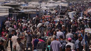 Palestinesi trasportano pacchi di cibo e aiuti umanitari a Rafah, 26 giugno 2025