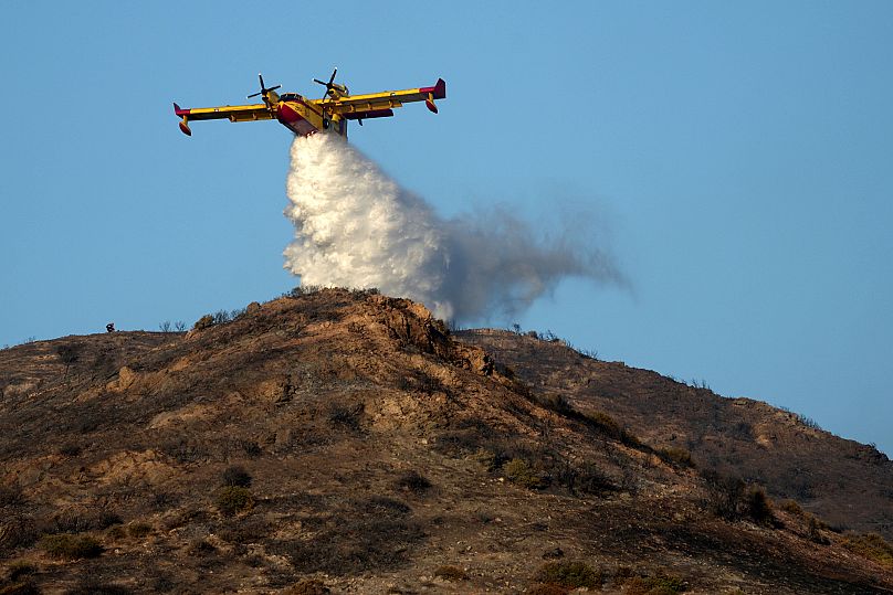 Un avion de pompiers lâche de l'eau sur une colline à Thymari, au sud d'Athènes, le jeudi 26 juin 2025