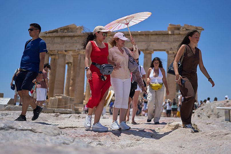 Des touristes se promènent au pied de la colline de l'Acropole, à Athènes, jeudi 26 juin 2025. La Grèce va traverser sa première vague de chaleur, avec es pics à 40°C.