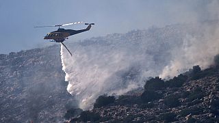 A firefighting helicopter drops water while battling a blaze in the seaside area of Charakas, south of Athens, Thursday, June 26, 2025,
