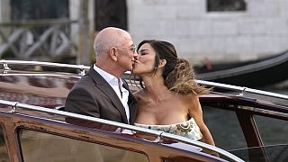Jeff Bezos, center left, and Lauren Sanchez, center right, kiss as they leave a hotel for their pre wedding reception, in Venice, Italy, Thursday, June 26, 2025.