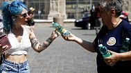 A civil protection volunteer distributes free bottles of water to tourists next to the Colosseum in Rome, Thursday, Aug. 12, 2021